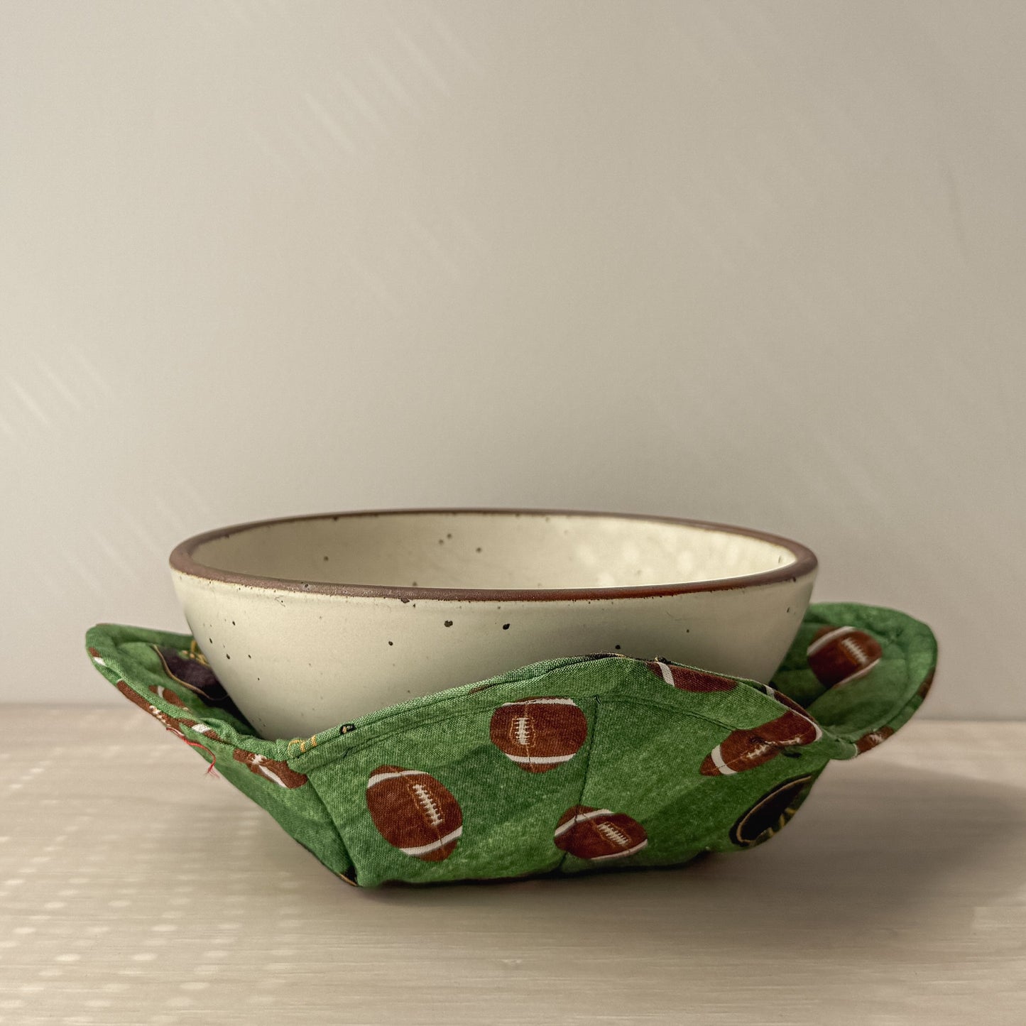 Ceramic bowl nestled in a Green football bowl cozy
