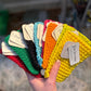 Hand holding a fan of colorful crocheted Scrubbies with tags.
