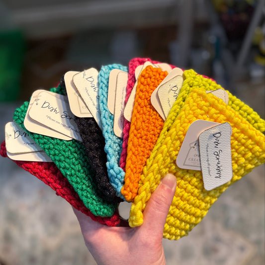 Hand holding a fan of colorful crocheted Scrubbies with tags.